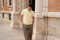 Man walking along a brick facade in a Freedom Fit Tee in Butter Yellow with rolled-up sleeves